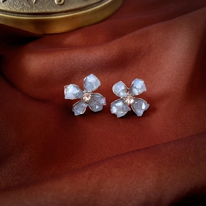 Detail of light blue flower stud earrings with crystal center on dark silk fabric