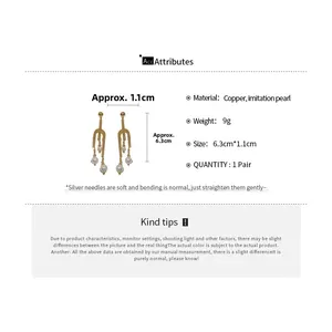 Detail view of gold U-shaped drop earrings with pearls showing dimensions 6.3cm by 1.1cm