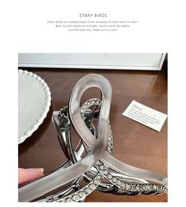 Close-up of a large silver hair claw clip with rhinestones and translucent grey accents