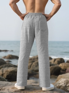 Detail view of light grey striped casual pants with a back pocket against a beach backdrop
