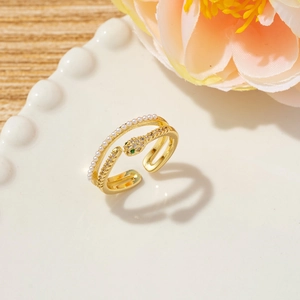 Close-up of golden snake ring with white pearls and sparkling zircon on ceramic tray