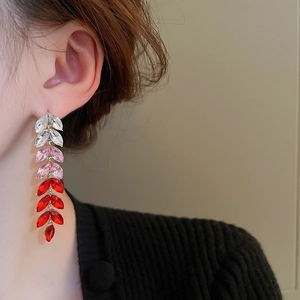 Macro shot of long leaf drop earrings with red and pink gradient crystals on silver pin