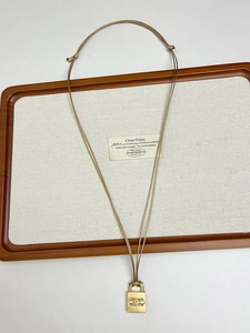 Macro detail of golden padlock pendant on a cord chain over a wooden tray