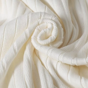 Detailed close-up of cream-white ribbed knit fabric showing soft texture and flexibility