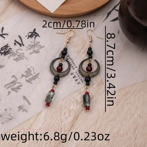 Detail view of long tassel earrings with beads on calligraphy paper, showing 8.7cm length