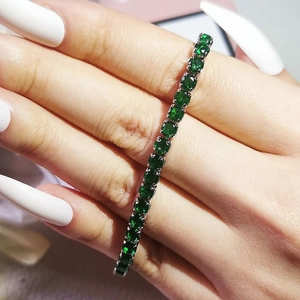 Close-up of sparkling green emerald tennis bracelet with silver prong setting