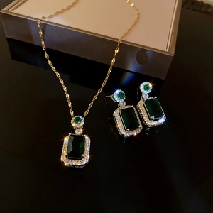 Vintage emerald square gemstone necklace and earrings set with diamonds on black background