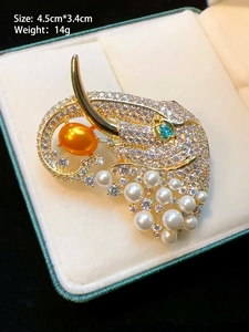 Macro shot of gold elephant brooch with emerald eyes and pearls on jewelry box pad