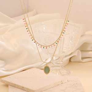 Détail du collier doré double rang avec gemme verte ovale et perles colorées