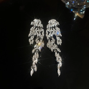 Macro detail of silver drop earrings with sparkling cubic zirconia on black mirror surface