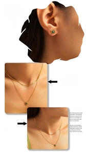 Detail of layered gold necklace and sunflower earrings with green gemstone on model
