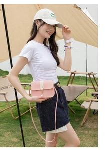Detail view of pink and white crossbody bag with gold pearl pendant in outdoor setting