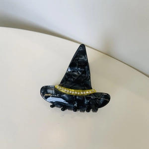 Detail view of a black marble texture witch hat hair claw with rhinestones and yellow band