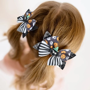 Close-up of Halloween hair bows with sequined pumpkin, ghost, and spider dolls