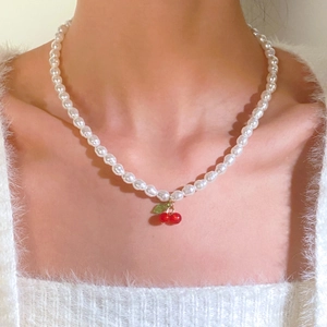 Close-up of sweet cherry pendant pearl necklace on model neck with soft velvet style