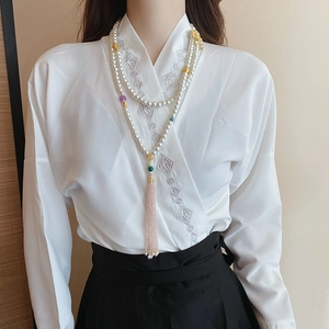 Close-up of multilayer pearl body chain with lotus pendant and pink crystal tassels