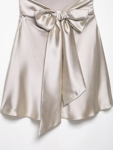 Detail of champagne satin skirt featuring a decorative large bow and silky texture