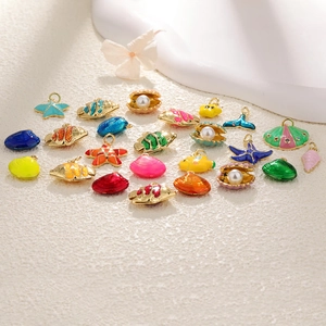 Macro detail of gold-plated shell and starfish charms with colorful enamel and pearls