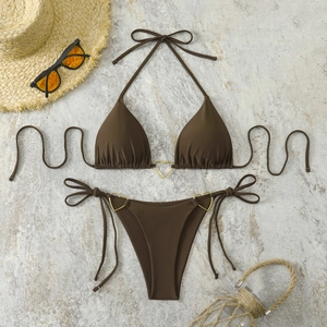 Detail of brown bikini set with golden heart rings on grey marble background