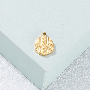Detailed view of a golden circular peace symbol pendant on a grey display block