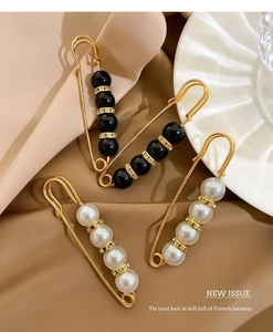 Detailed view of four pearl brooches with rhinestones on silk, including black and white