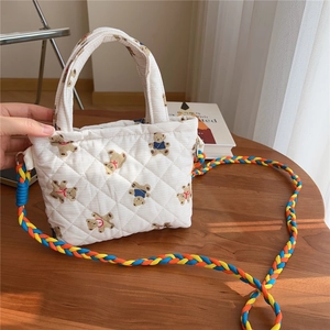 Close-up of quilted floral bear pattern fabric and colorful braided strap of crossbody bag