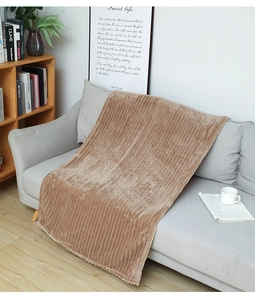 Detail of light brown flannel throw blanket with striped texture draped on a gray sofa