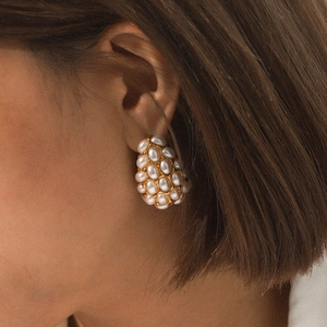 Gold stainless steel teardrop earrings with embedded white pearls worn by a model