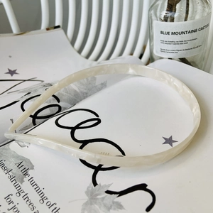Detailed texture of cream white marble acetate headband on an aesthetic magazine background