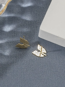 Close-up of golden leaf-shaped titanium steel stud earrings on a blue textured base