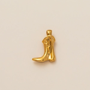 Golden cowboy boot pendant with U-shaped zircon on a clean beige background