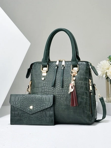 Detail of dark green crocodile pattern handbag and matching wallet with gold hardware