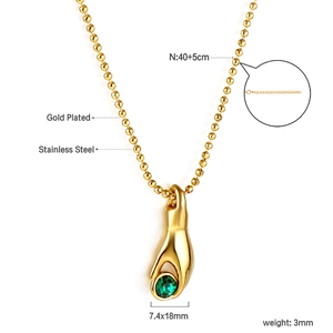 Detail of gold plated stainless steel necklace featuring a hand pendant with green gemstone
