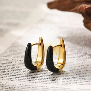 Macro view of U-shaped gold earrings with black enamel finish on vintage paper