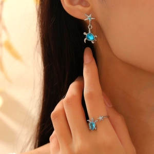 Silver sea turtle and starfish jewelry set with blue gems worn by a model