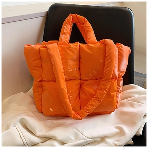 Detail of vibrant orange quilted puffer tote bag with padded handles and thick strap