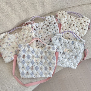 Detail showing five quilted tote bags with cartoon patterns and pink woven handles