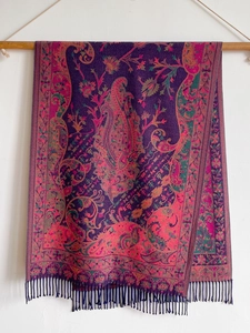 Macro detail of ethnic paisley pattern and fringes on purple pashmina style shawl
