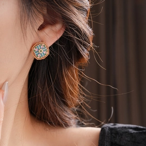 Close-up of vintage diamond-shaped flower earrings with colorful enamel on a model