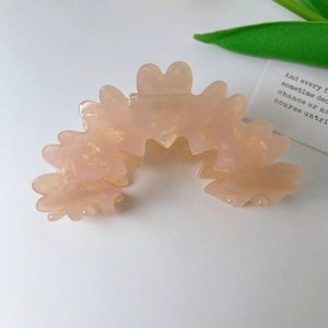 Detail of wavy acetate claw clip in translucent peach pink with pearlescent finish