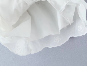 Detailed macro view of white embroidered floral lace and hollow-out scallop edge fabric