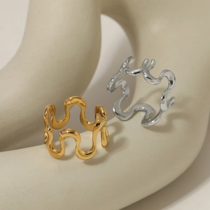 Artistic wavy metal rings in gold and silver finish on elegant white sculpture base
