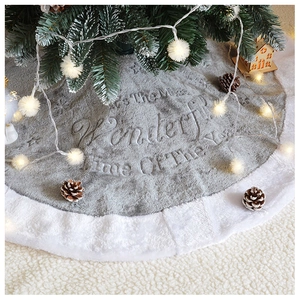 Detail of grey plush Christmas tree skirt with white faux fur trim and holiday text