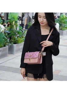 Detailed view of pink sequined crossbody bag with gold heart buckle and leather chain strap