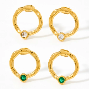 Strukturierte goldene Ohrstecker mit Zirkonia und grünen Edelsteinen auf weißem Grund