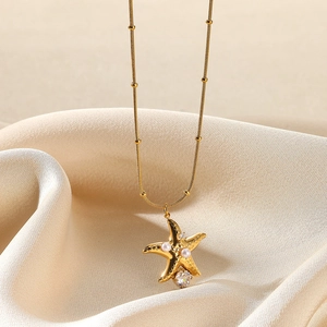 Detailed shot of golden starfish necklace with white pearls and sparkling zircon stone