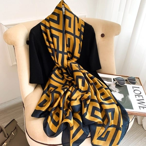 Elegant yellow and black houndstooth silk scarf draped over a chair with fashion accessories