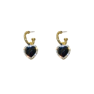 Gold C-hoop earrings with black rhinestone heart pendants in a minimalist fashion style