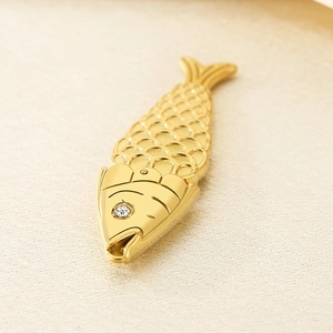 Détail macro du pendentif poisson doré avec texture d'écailles et œil en gemme