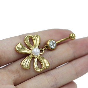 Detailed view of a gold flower navel piercing with white pearl and cubic zirconia stone
